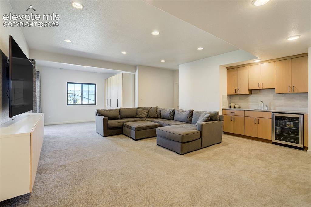 Image 39 of 50: Spacious recreation room featuring recessed lighting, plush carpeting, a bu