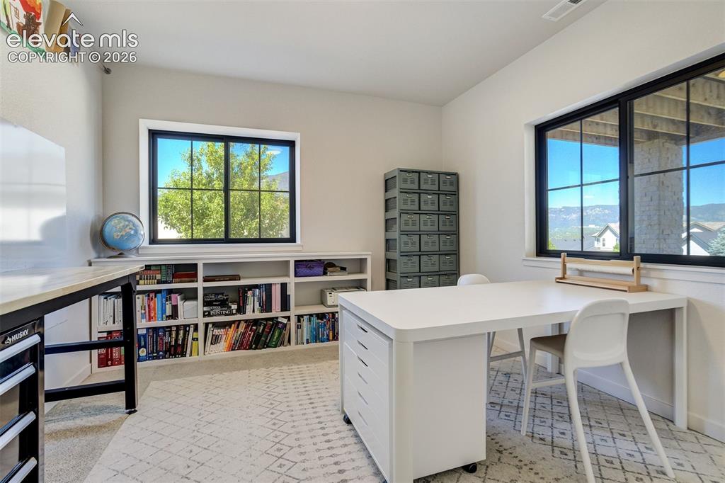 Image 41 of 50: Spacious room featuring broad windows with dark frames, built-in shelving,