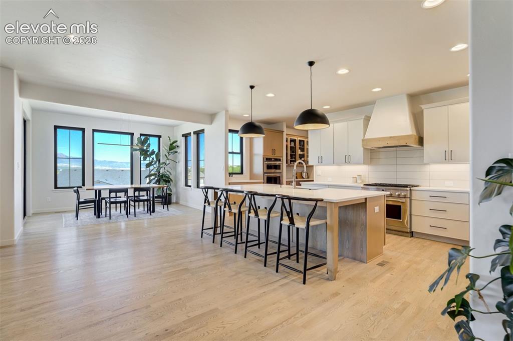 Image 9 of 50: Open-concept kitchen and dining area featuring light wood-finish flooring,