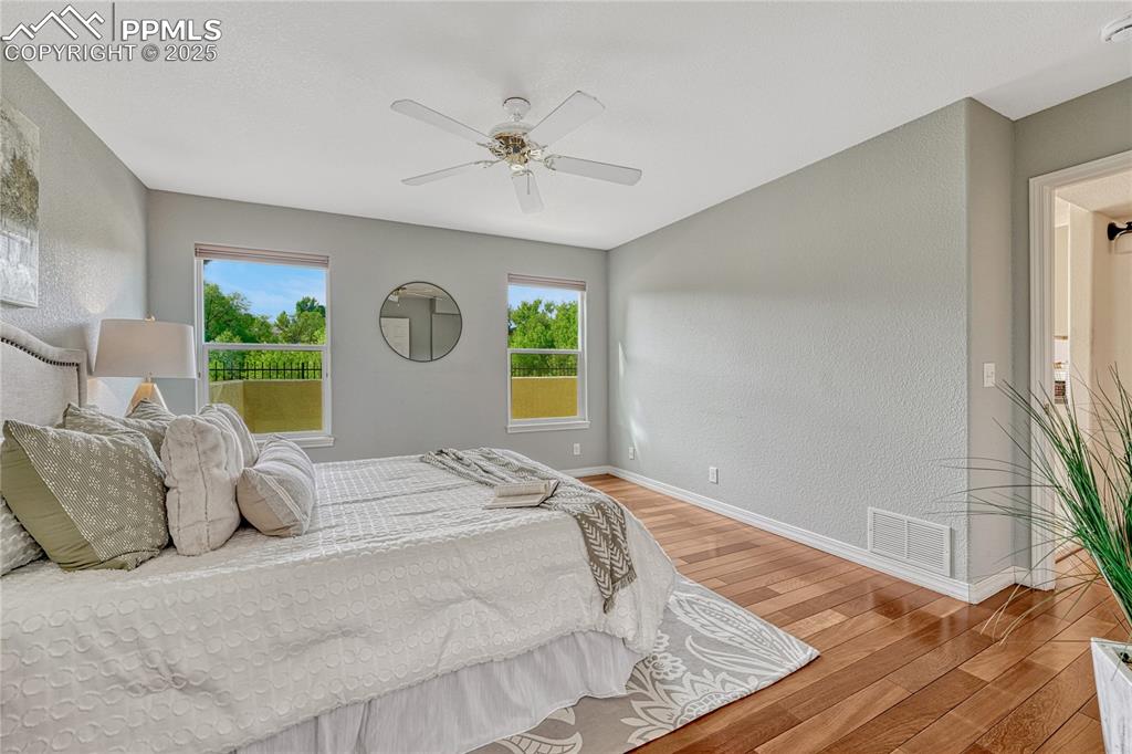 Image 21 of 47: Natural wood floors, ceiling fan and large windows bring nature into the sp