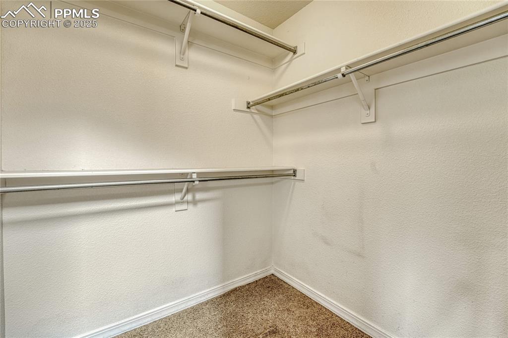 Image 24 of 47: Walk-in closet with multiple shelves and rods for clothes storage and organ