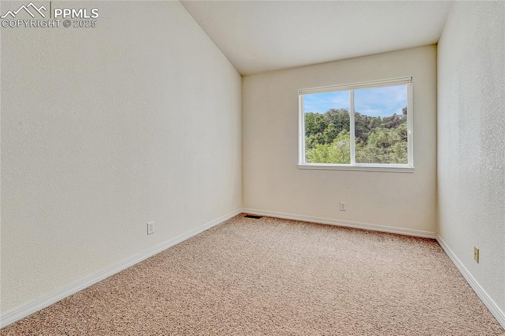 Image 31 of 47: Carpeted floors and a sliding window overlooking the back