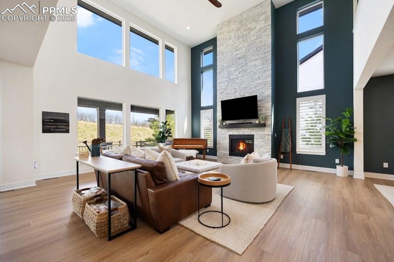 Image 11 of 49: Living room featuring a towering ceiling, wood finished floors, a fireplace