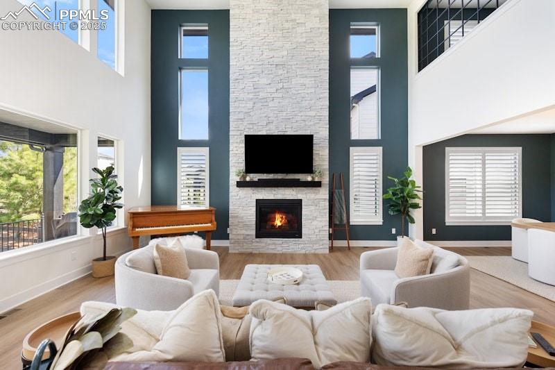 Image 12 of 49: Living area with a towering ceiling, plenty of natural light, and a stone f