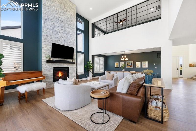 Image 13 of 49: Living area featuring a towering ceiling, wood finished floors, a fireplace
