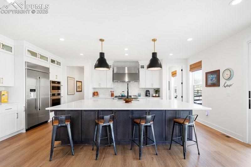 Image 15 of 49: Kitchen featuring stainless steel appliances, wall chimney exhaust hood, li