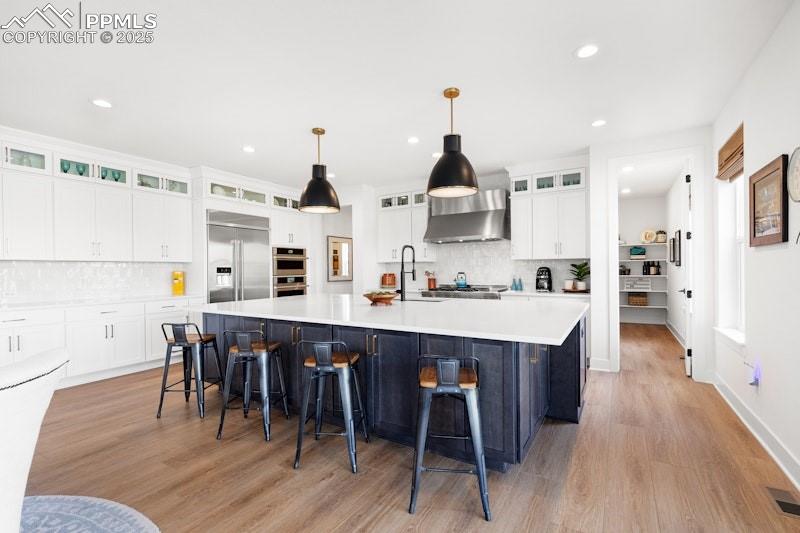 Image 16 of 49: Kitchen with stainless steel appliances, wall chimney exhaust hood, a sink,