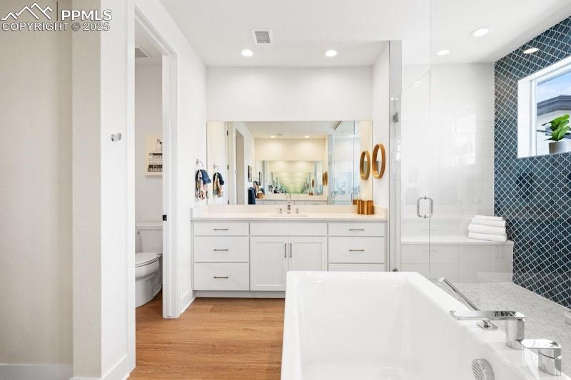 Image 27 of 49: Full bath featuring a stall shower, a soaking tub, vanity, toilet, and wood