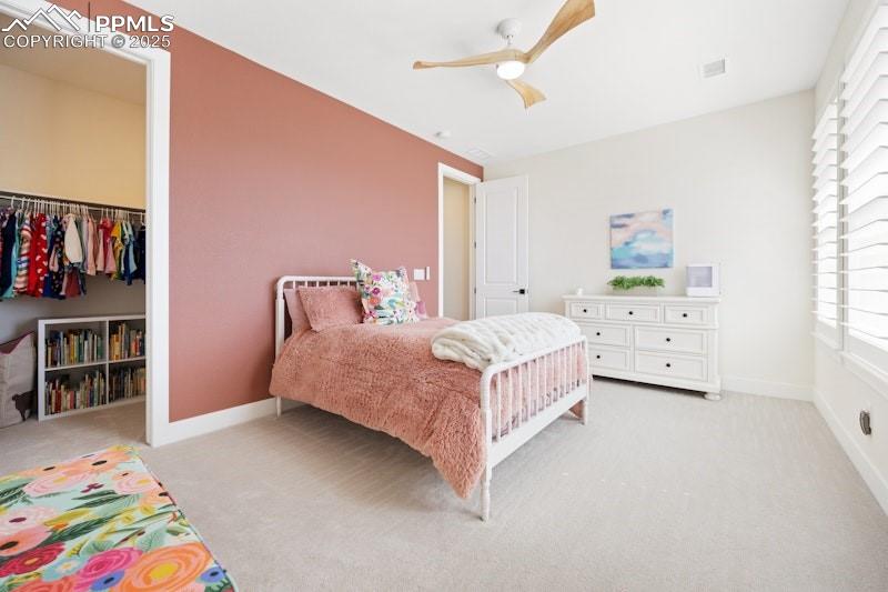 Image 31 of 49: Bedroom featuring light colored carpet, multiple windows, and a walk in clo