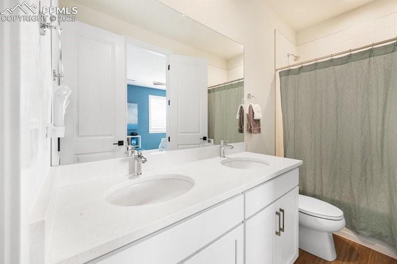 Image 37 of 49: Full bath with toilet, double vanity, and wood finished floors