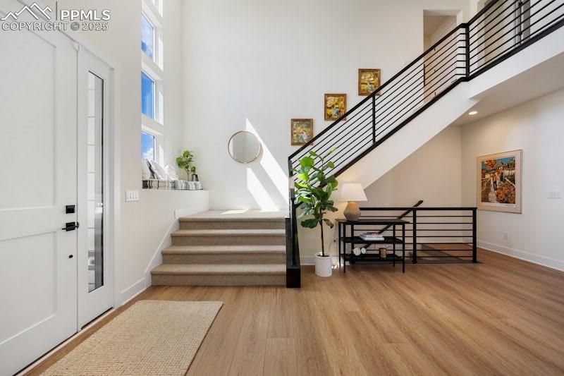 Image 8 of 49: Entrance foyer with a high ceiling, stairway, wood finished floors, healthy