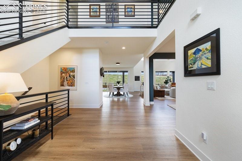 Image 9 of 49: Hallway with an upstairs landing, wood finished floors, baseboards, and a t