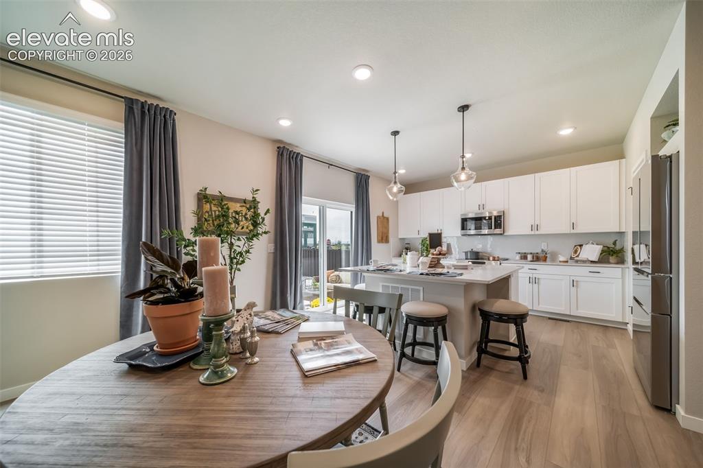 Image 15 of 45: Open-concept kitchen and dining area featuring light wood-finish flooring