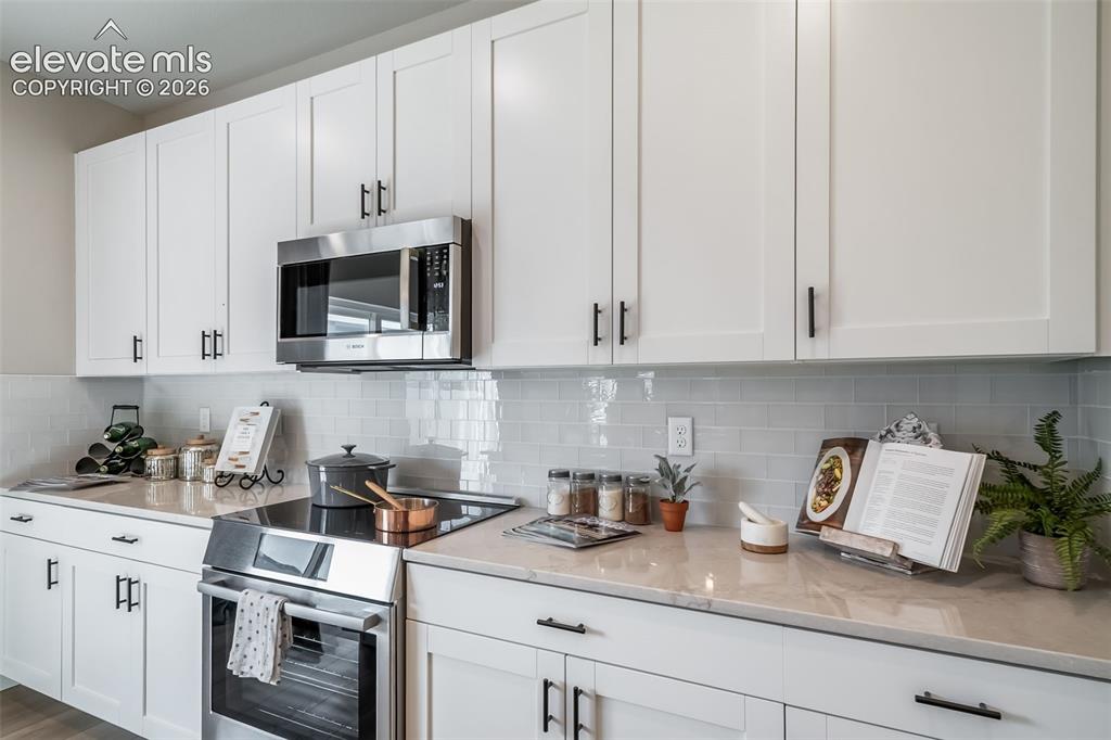 Image 29 of 45: Kitchen featuring extensive white shaker cabinetry, stainless steel applian