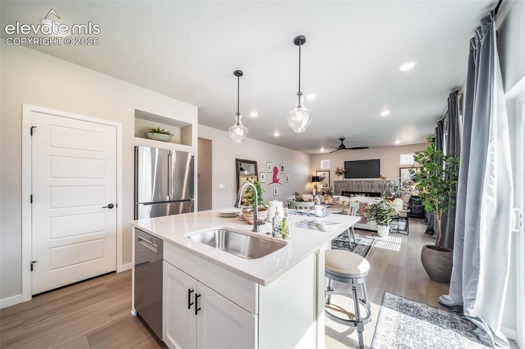 Image 31 of 45: Kitchen island featuring a stainless steel sink, white countertop, white ca