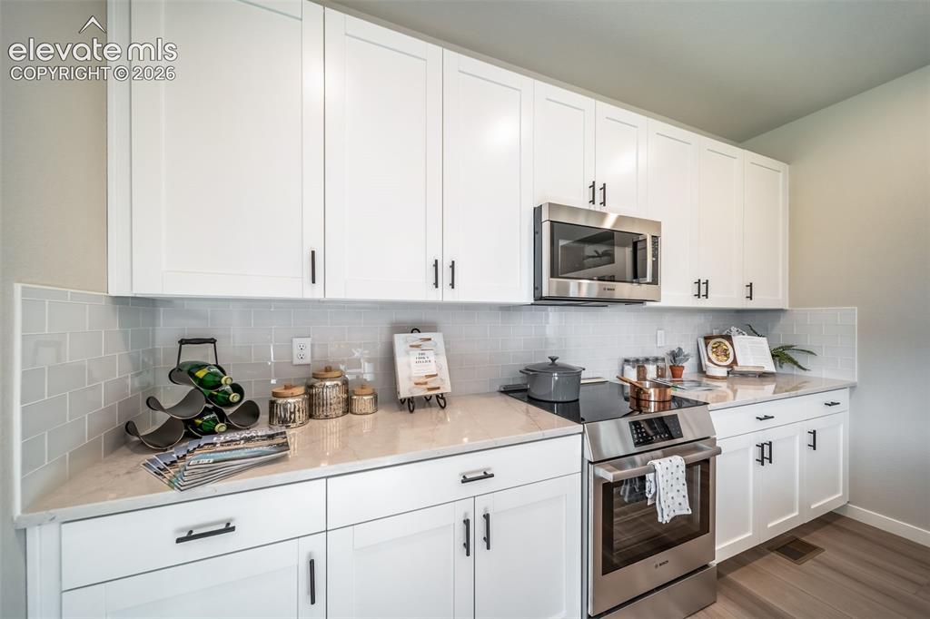 Image 32 of 45: Contemporary kitchen featuring white shaker cabinetry with matte black hard