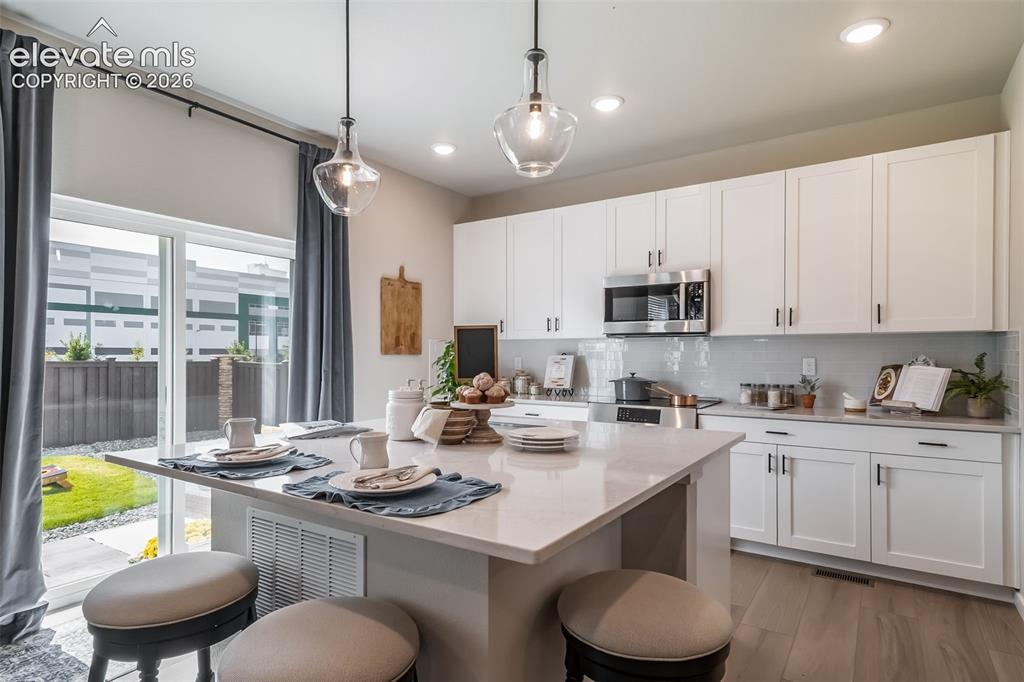 Image 33 of 45: Kitchen featuring a central island with countertop seating, white shaker-st