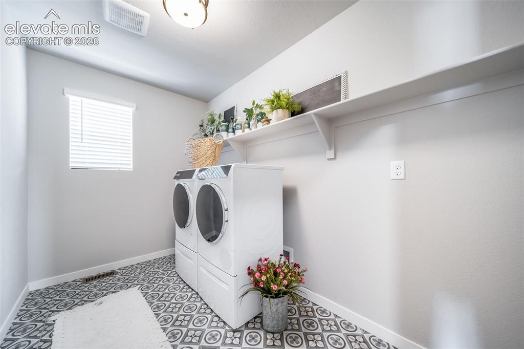Image 35 of 45: Laundry room featuring patterned floor tiles, a window with blinds, overhea