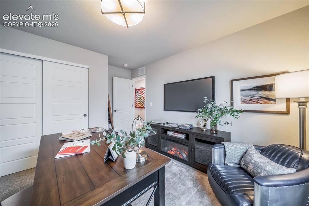 Image 8 of 45: Versatile room featuring a large wood-finish desk, built-in shelving, slidi