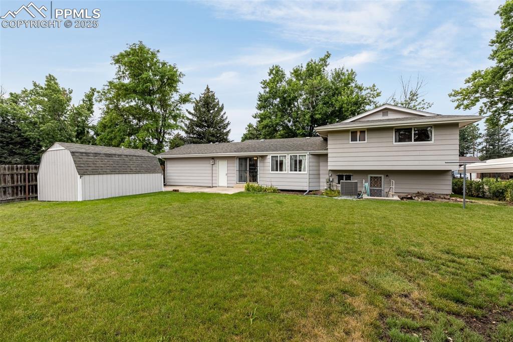 Image 18 of 19: Back of property featuring a storage unit and a patio.