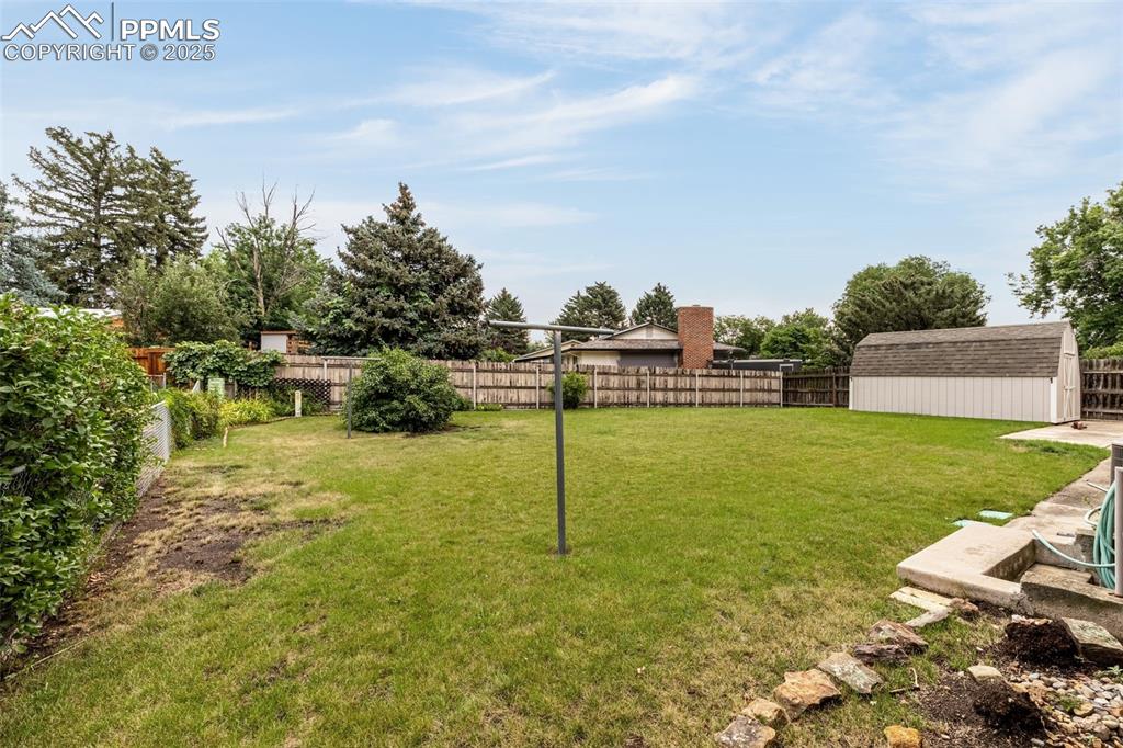Image 19 of 19: Fenced backyard with a utility shed and clothes line.