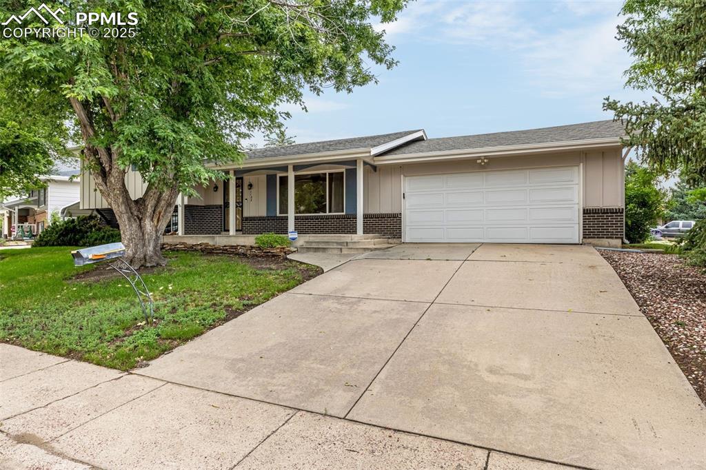 Image 2 of 19: Ranch-style house featuring a porch, brick siding, an attached garage, conc