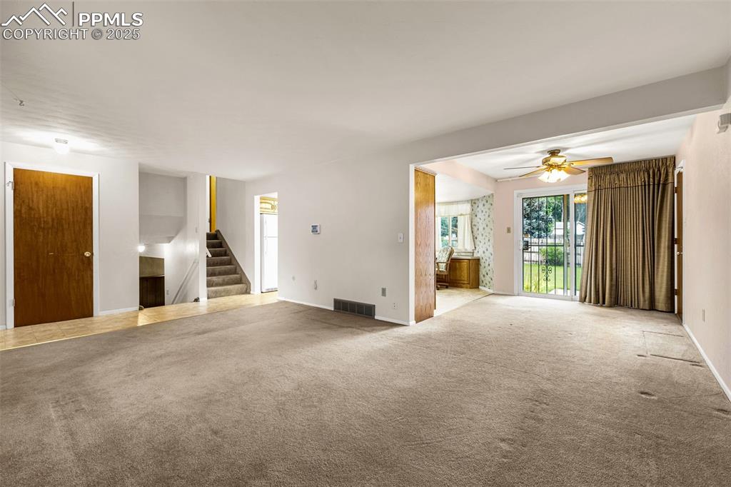 Image 4 of 19: Unfurnished living room & dining area with carpet flooring and a ceiling fa