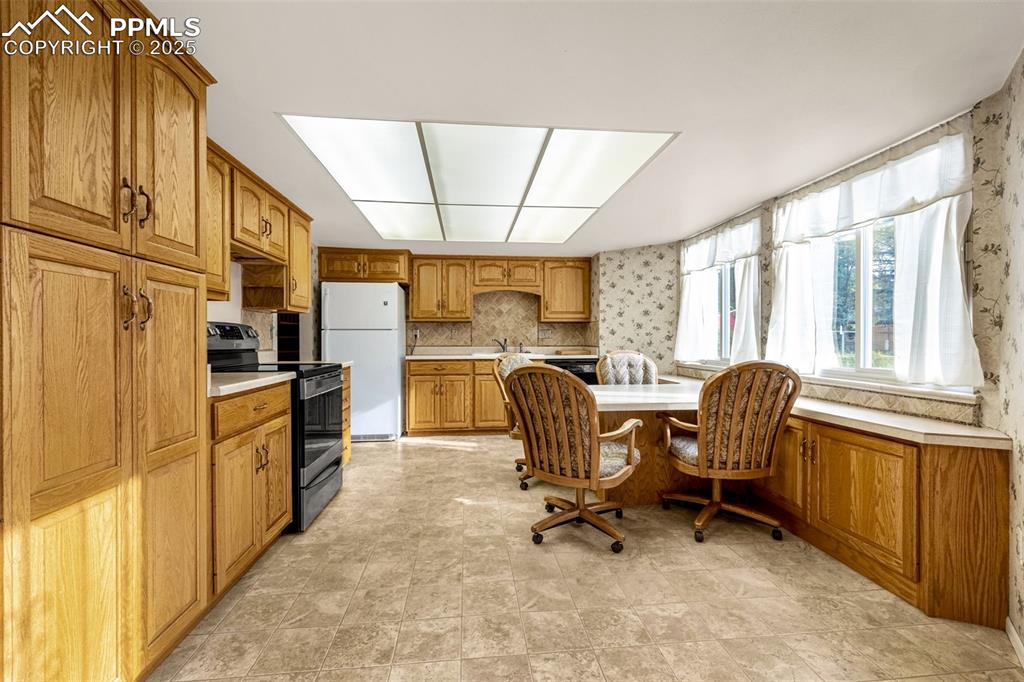 Image 6 of 19: Kitchen featuring glass top range with  light countertops, brown cabinets, 