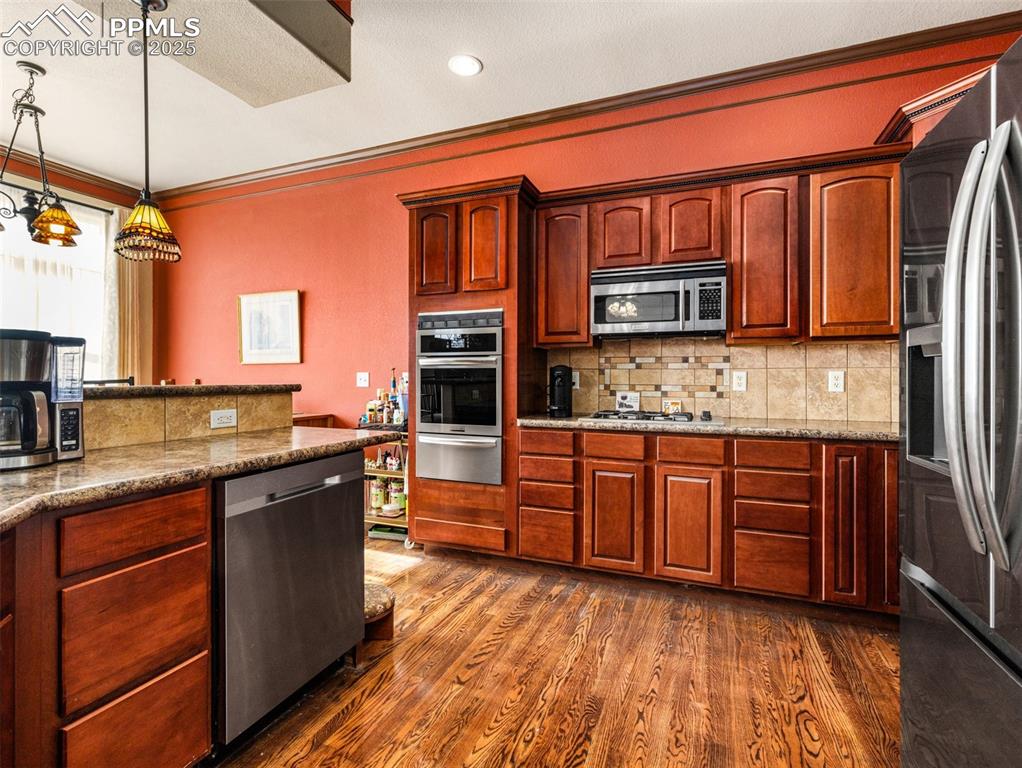 Image 11 of 48: Kitchen featuring decorative backsplash, crown molding, stainless steel app