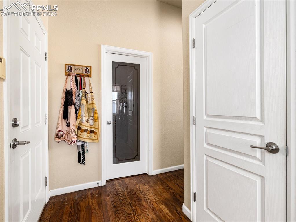 Image 14 of 48: Hallway with baseboards and dark wood-style flooring