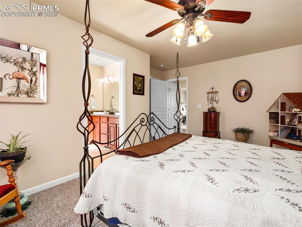 Image 16 of 48: Bedroom with ensuite bath, carpet, and a ceiling fan