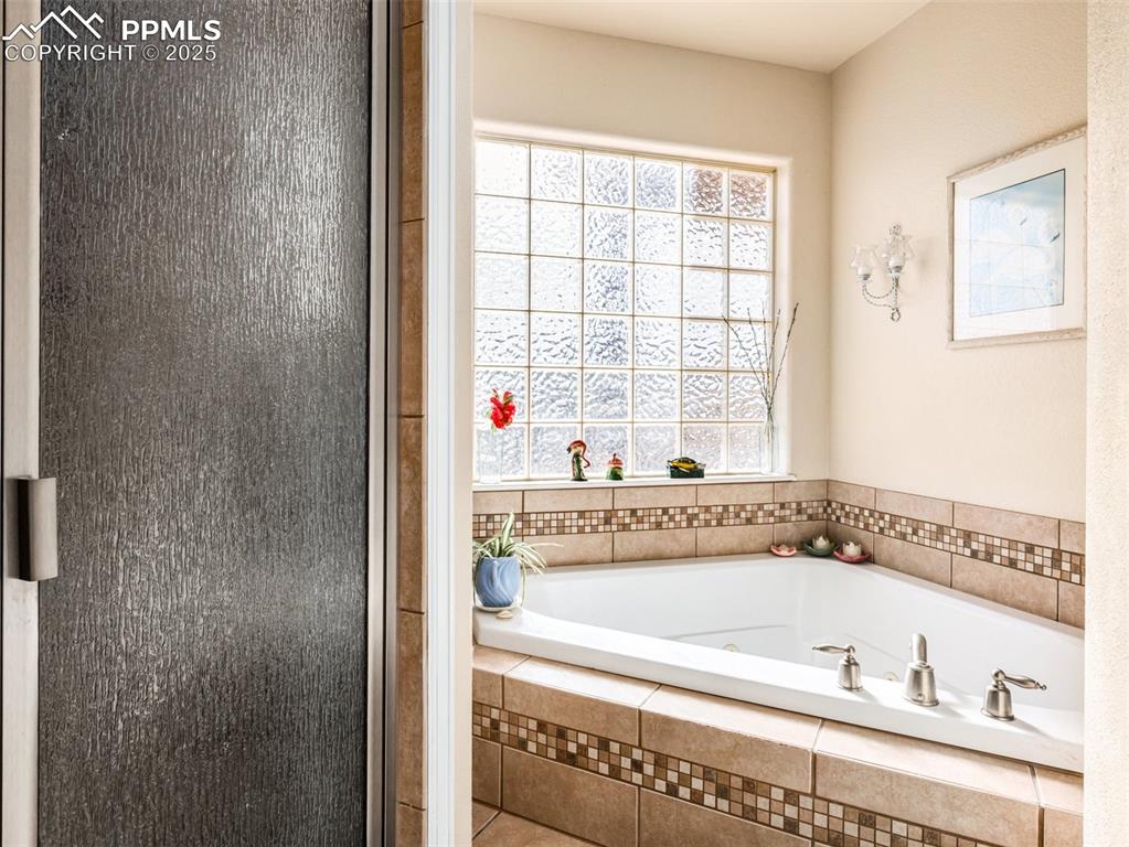 Image 18 of 48: Bathroom featuring a bath and a stall shower