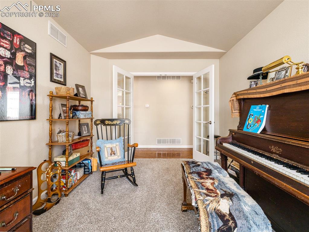 Image 23 of 48: Sitting room with vaulted ceiling and french doors