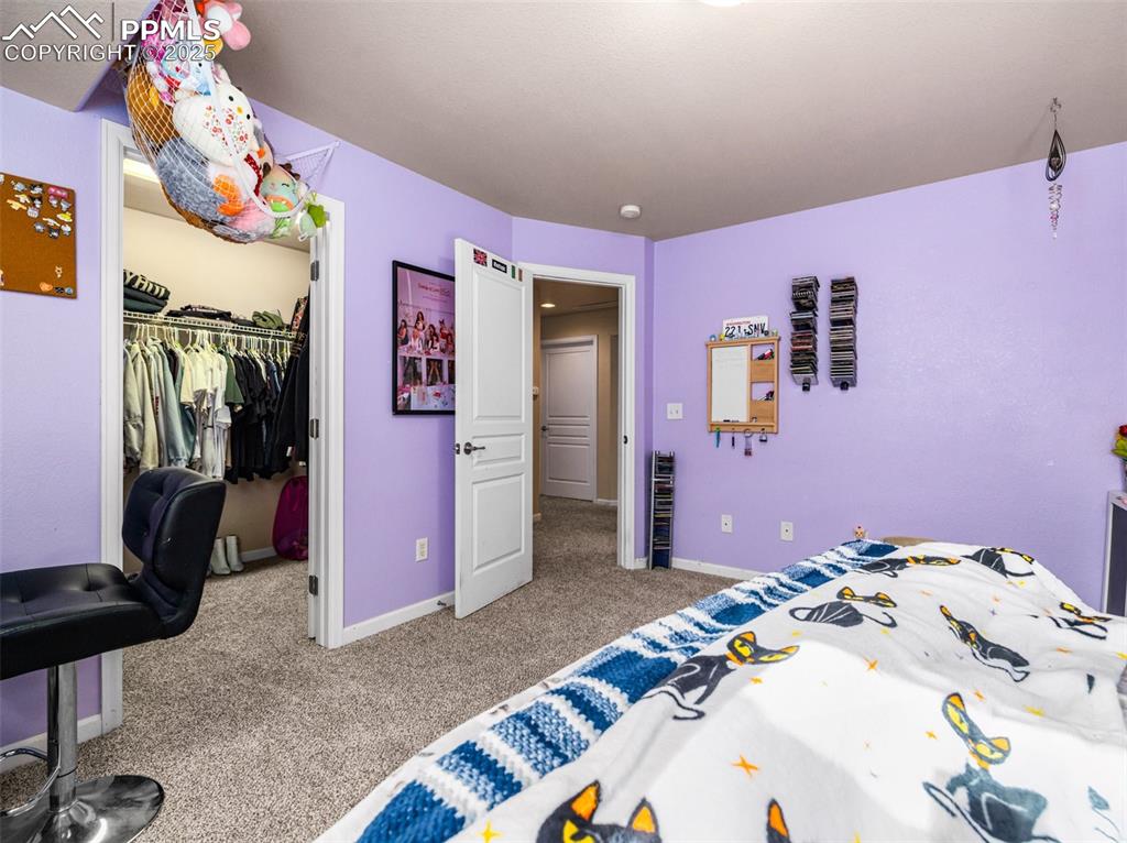 Image 30 of 48: Bedroom featuring light carpet and a walk in closet