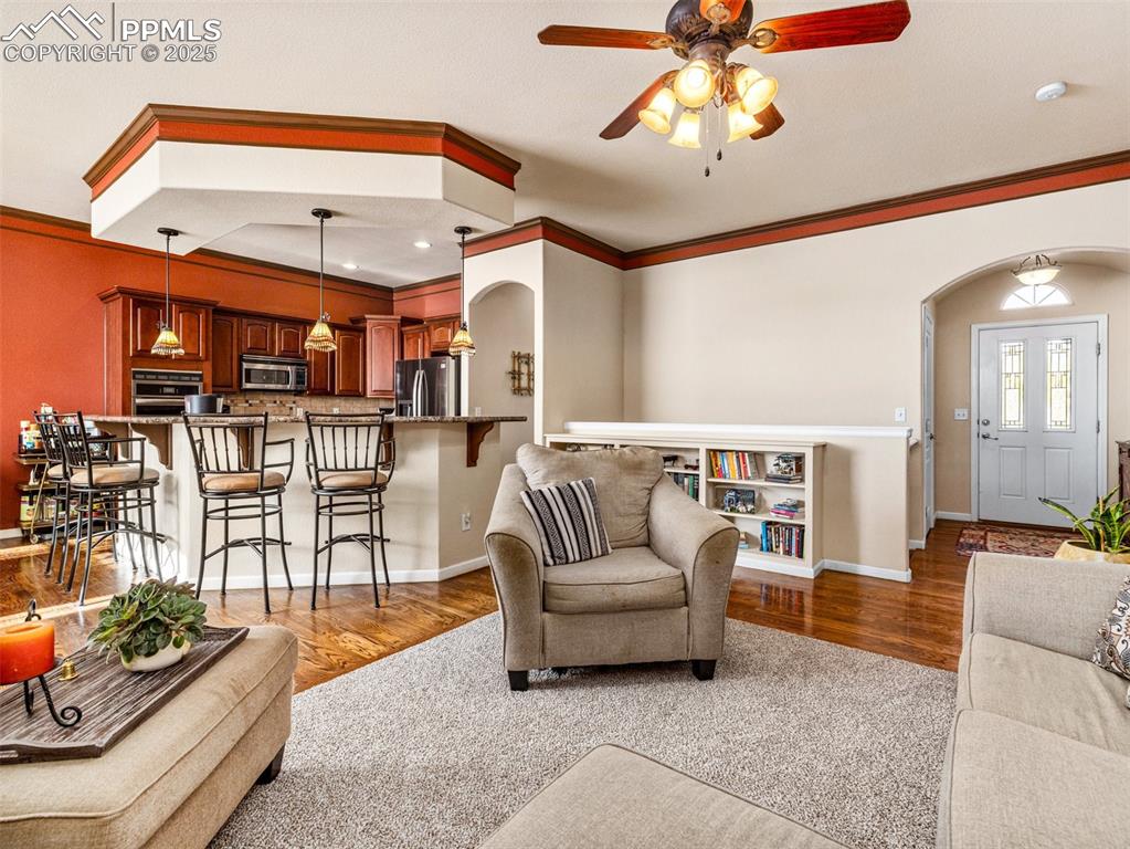Image 4 of 48: Living room featuring arched walkways, ornamental molding, ceiling fan, lig