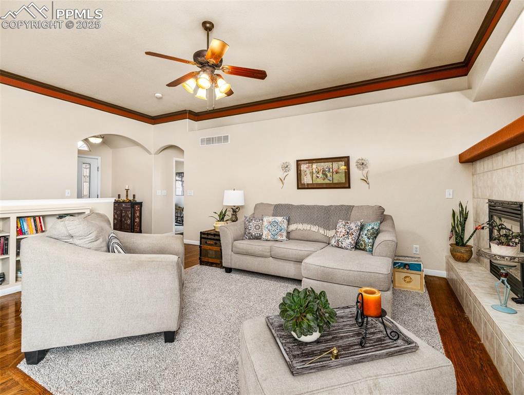 Image 5 of 48: Living room featuring arched walkways, dark wood-style flooring, crown mold