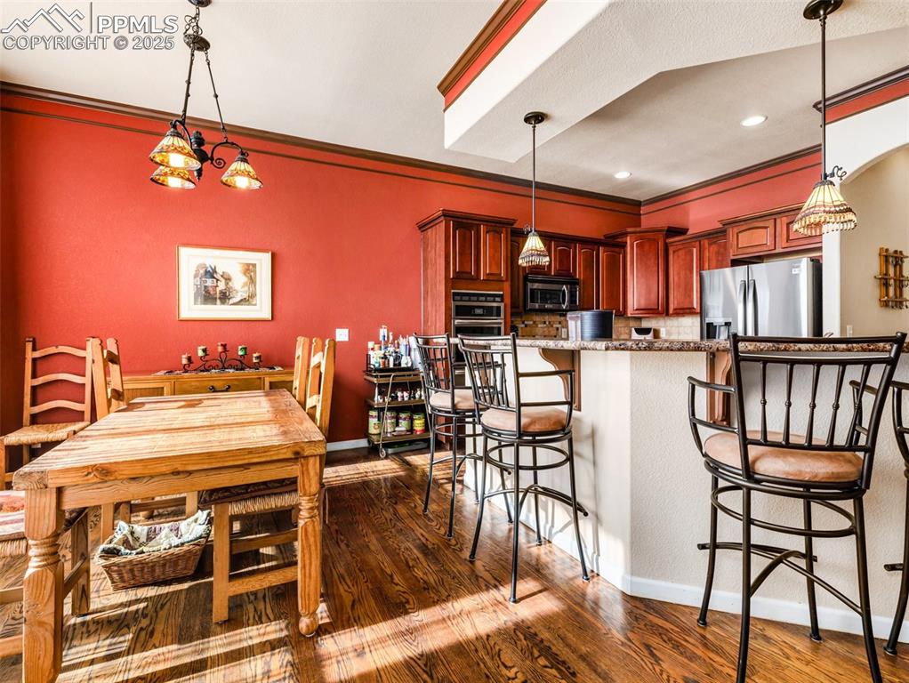 Image 6 of 48: Kitchen featuring ornamental molding, pendant lighting, dark wood-style flo