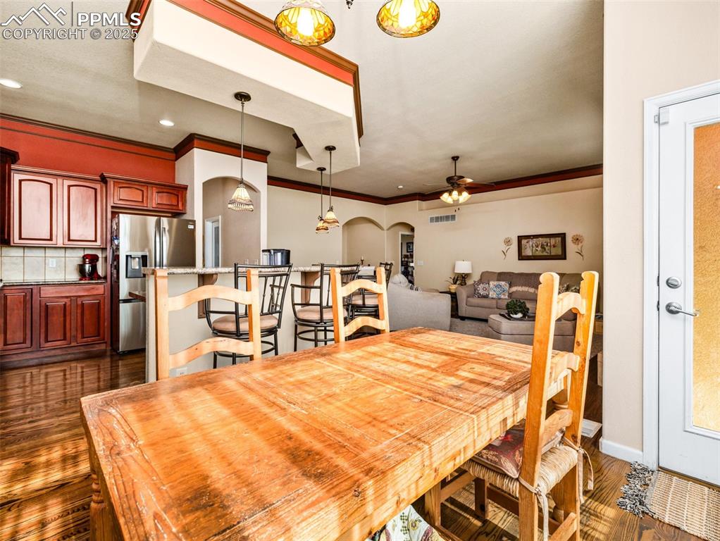 Image 7 of 48: Dining room with arched walkways, crown molding, dark wood finished floors,