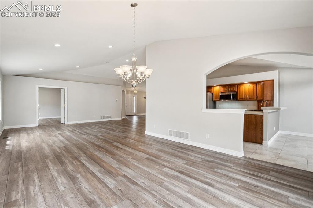Image 11 of 49: Unfurnished living room featuring visible vents, arched walkways, light woo