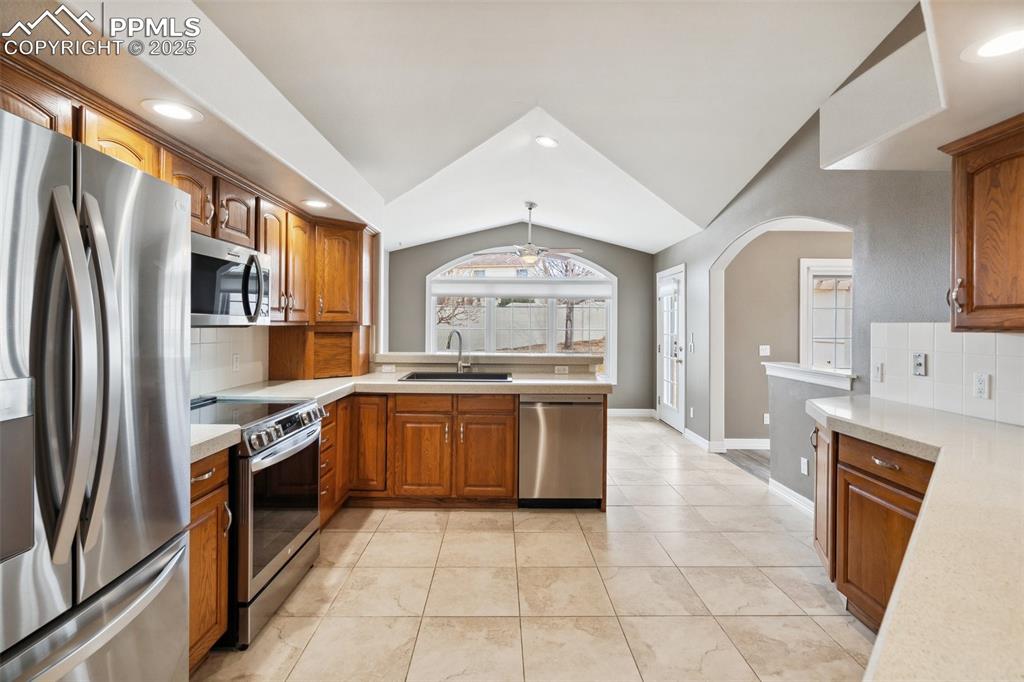 Image 14 of 49: Kitchen featuring light countertops, brown cabinets, stainless steel applia