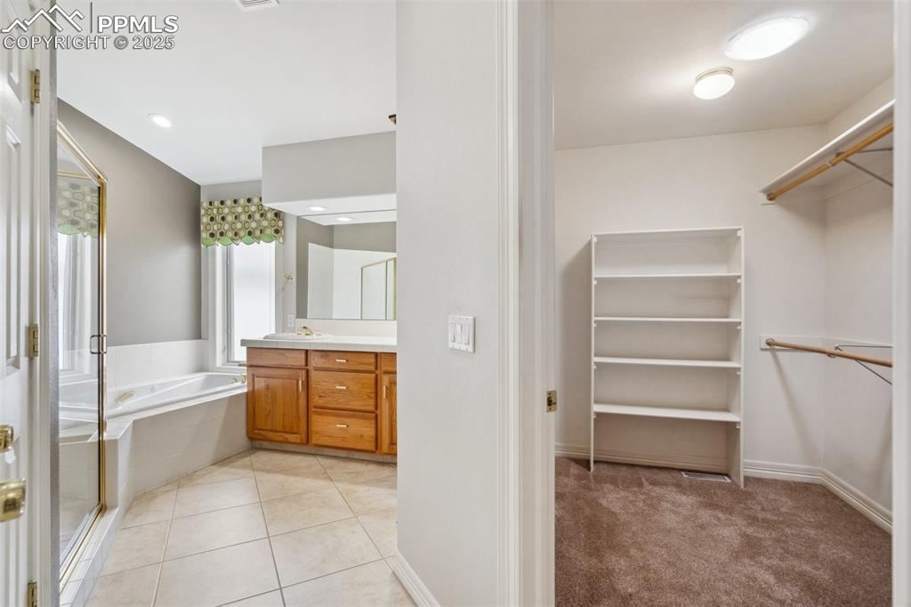 Image 18 of 49: Bathroom featuring vanity, a walk in closet, tile patterned floors, a stall