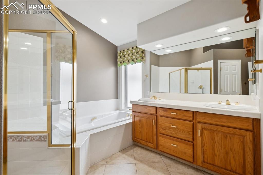 Image 19 of 49: Bathroom featuring double vanity, tile patterned floors, a sink, a stall sh