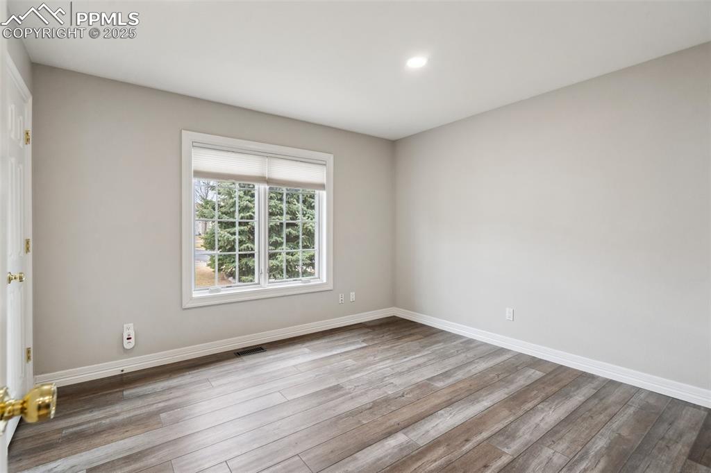 Image 21 of 49: Empty room featuring baseboards, visible vents, wood finished floors, and r