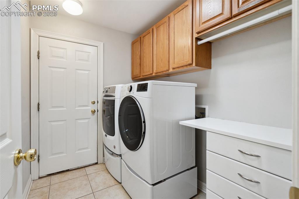 Image 23 of 49: Laundry room with light tile patterned flooring, cabinet space, and washer 