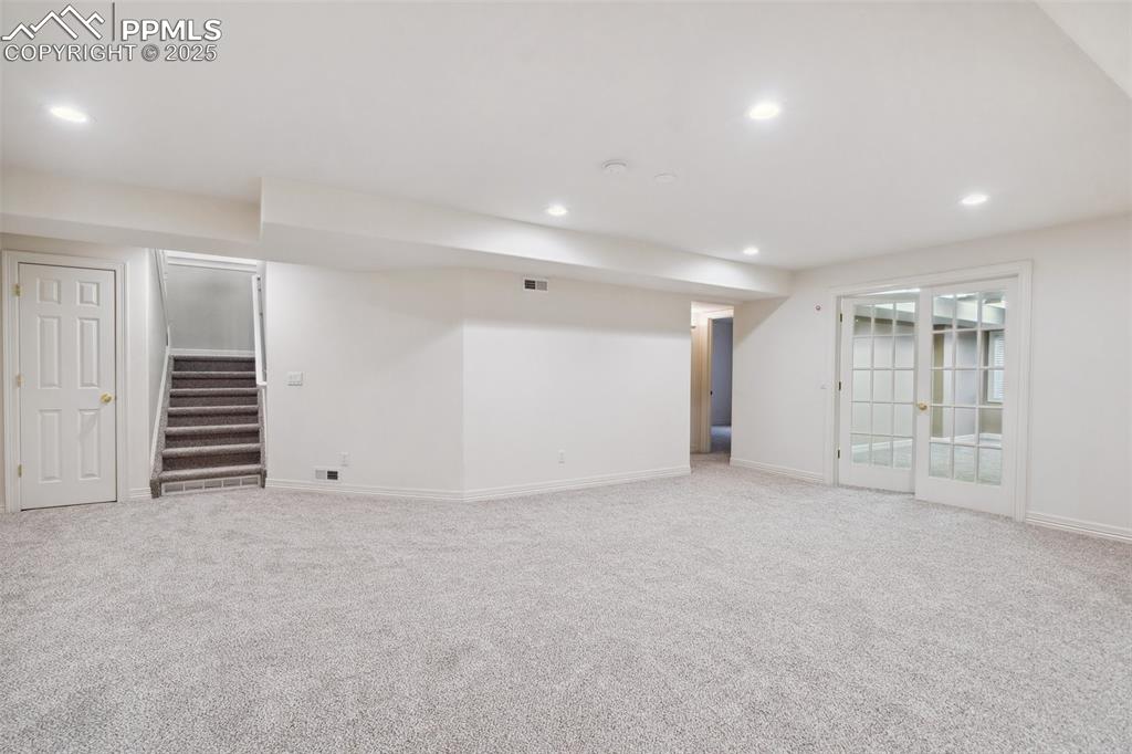 Image 25 of 49: Finished basement with light carpet, stairs, and recessed lighting