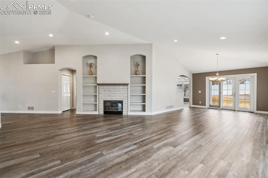 Image 5 of 49: Unfurnished living room featuring dark wood finished floors, lofted ceiling