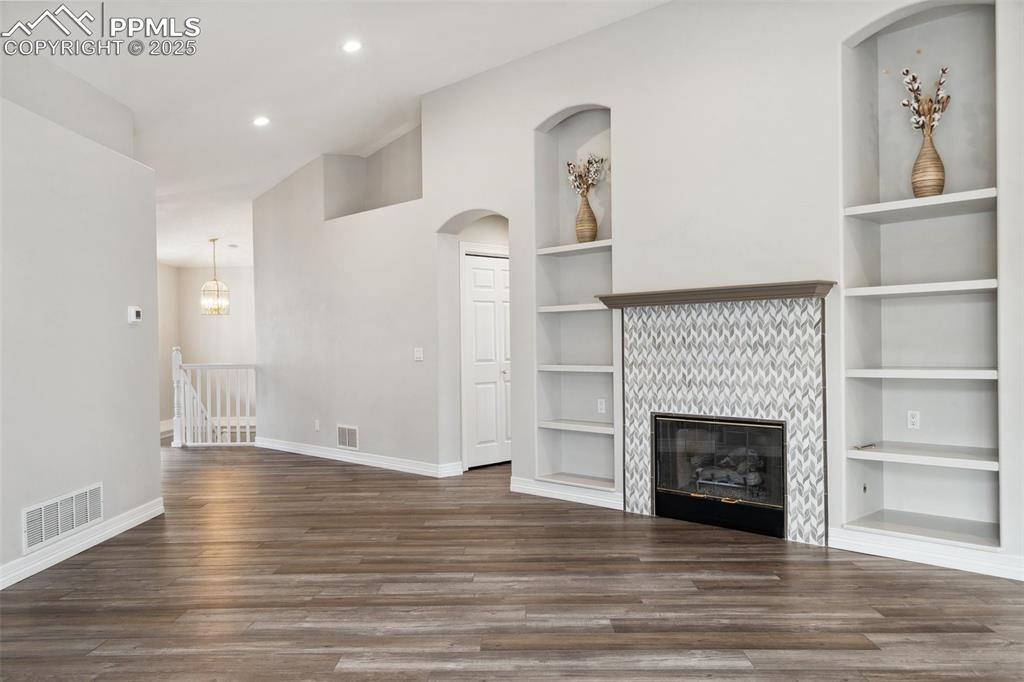 Image 6 of 49: Unfurnished living room with baseboards, built in shelves, visible vents, a
