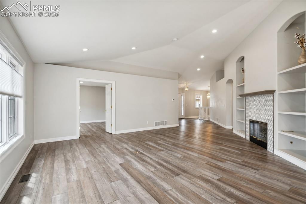 Image 7 of 49: Unfurnished living room with baseboards, lofted ceiling, visible vents, and