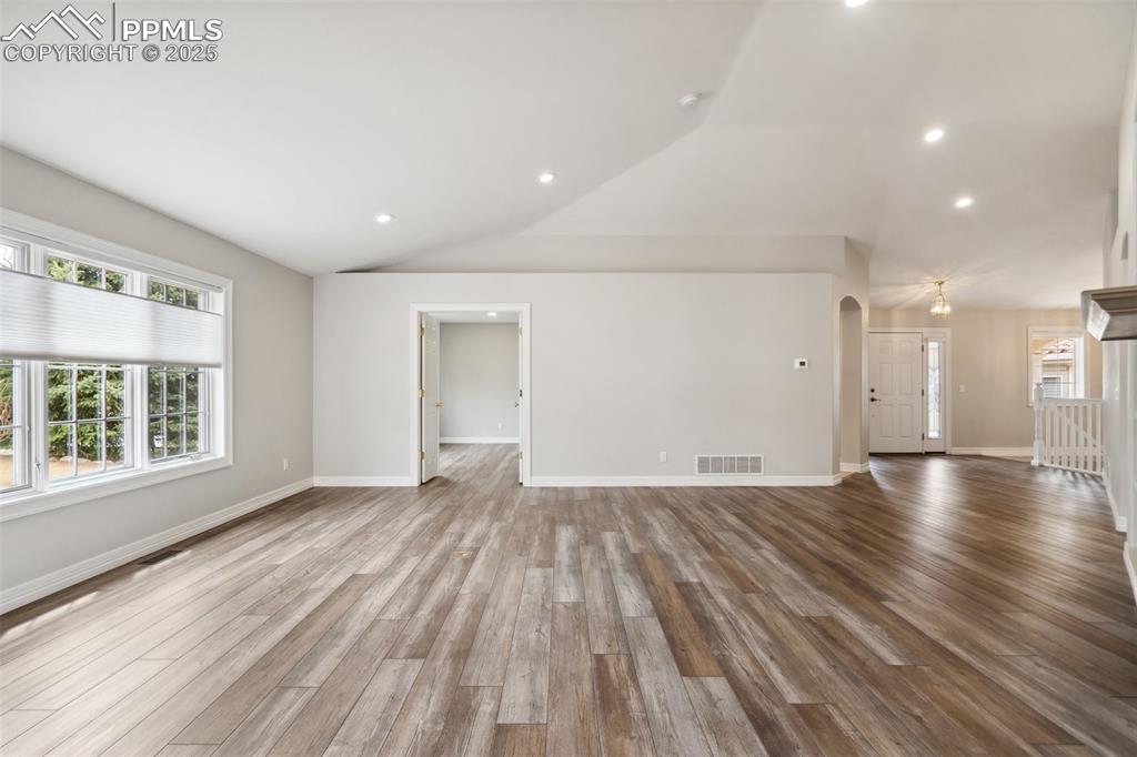 Image 8 of 49: Unfurnished living room with wood finished floors, baseboards, vaulted ceil