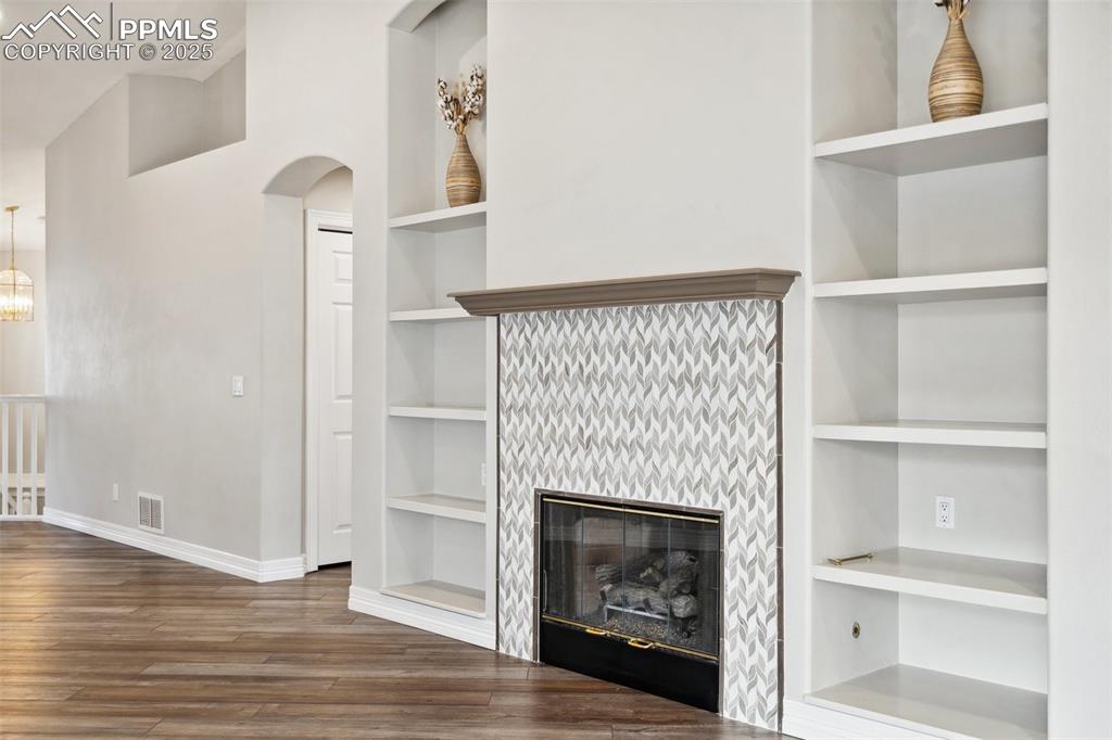 Image 9 of 49: Unfurnished living room with visible vents, arched walkways, wood finished 